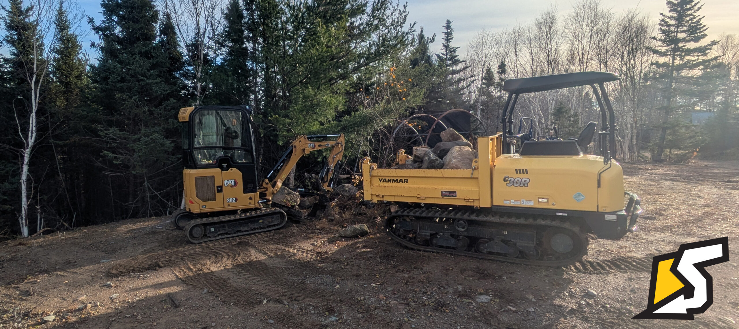 Compact excavator and tracked carrier completing property site work